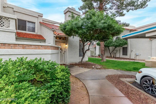 a front view of a house with a garden and tree