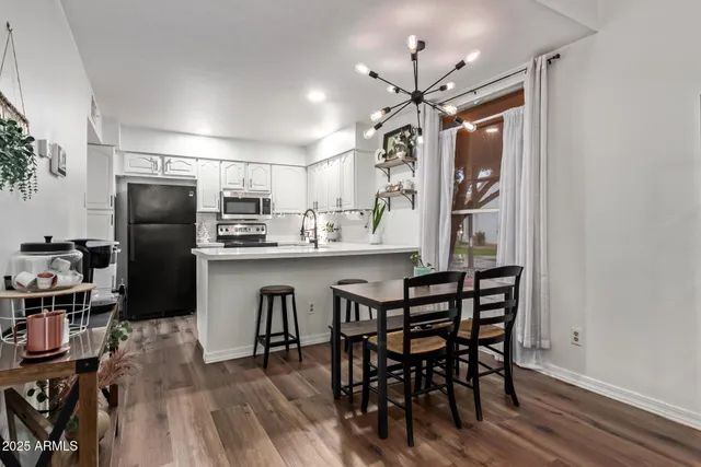 a kitchen with stainless steel appliances a dining table chairs refrigerator and cabinets