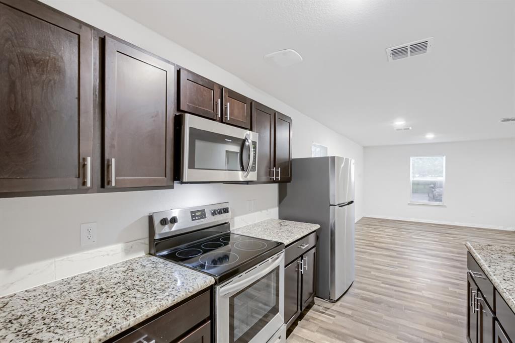 903 Olive Street Waco, TX 76704 - Photo 10 of 15 a kitchen with granite countertop stainless steel appliances and wooden cabinets