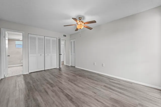 a view of a room with wooden floor and a ceiling fan