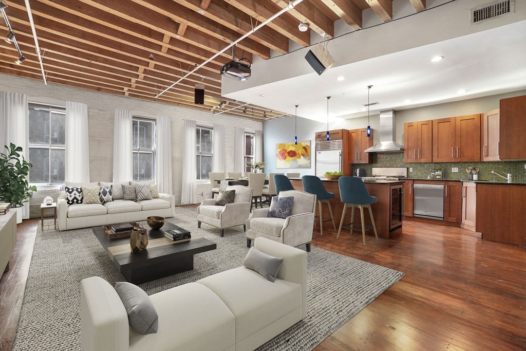 a living room with furniture kitchen view and a wooden floor