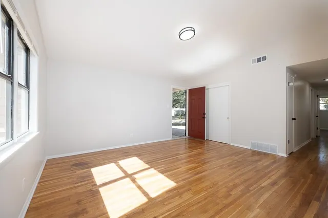 an empty room with wooden floor and windows