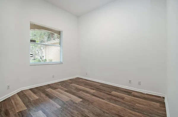 a view of an empty room with wooden floor and closet