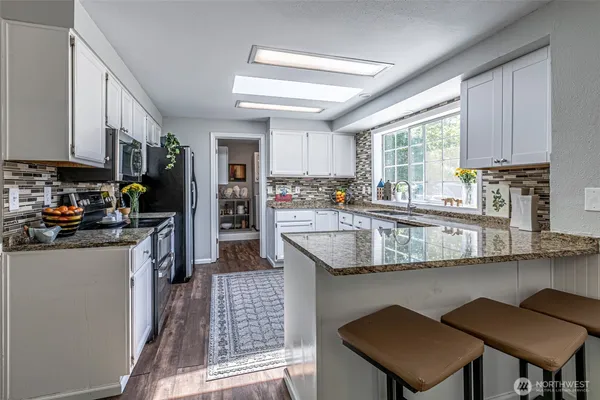 a kitchen with stainless steel appliances granite countertop a stove a sink and a refrigerator