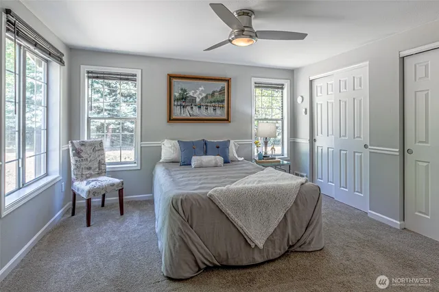 a bedroom with a bed painting on wall and windows