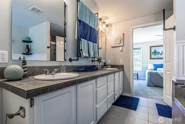 a spacious bathroom with a double vanity sink a mirror and a shower