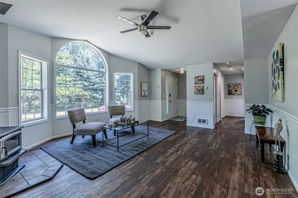 a living room with furniture floor to ceiling window and wooden floor