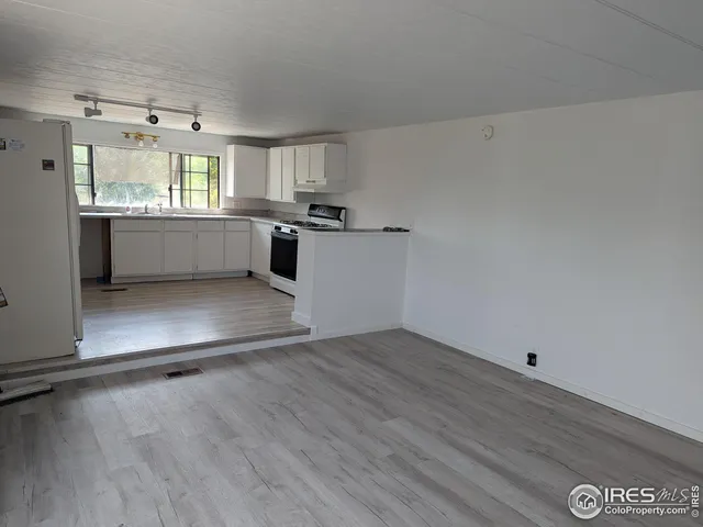 a view of a kitchen with wooden floor and electronic appliances