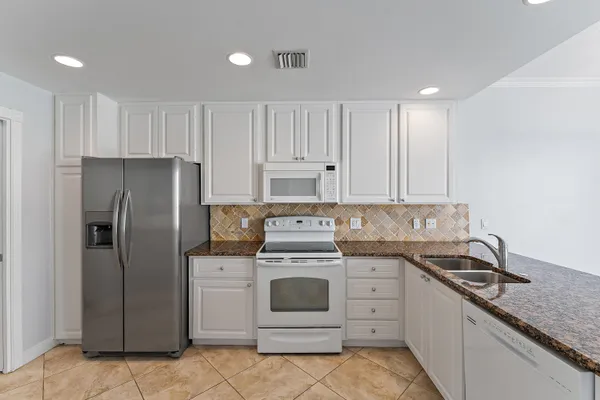 a kitchen with white cabinets and white appliances