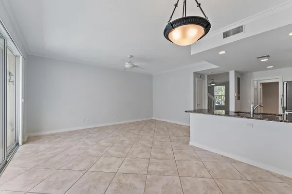 a view of an empty room with chandelier fan and window