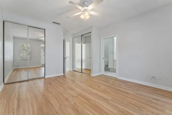 a view of an empty room with wooden floor and a ceiling fan