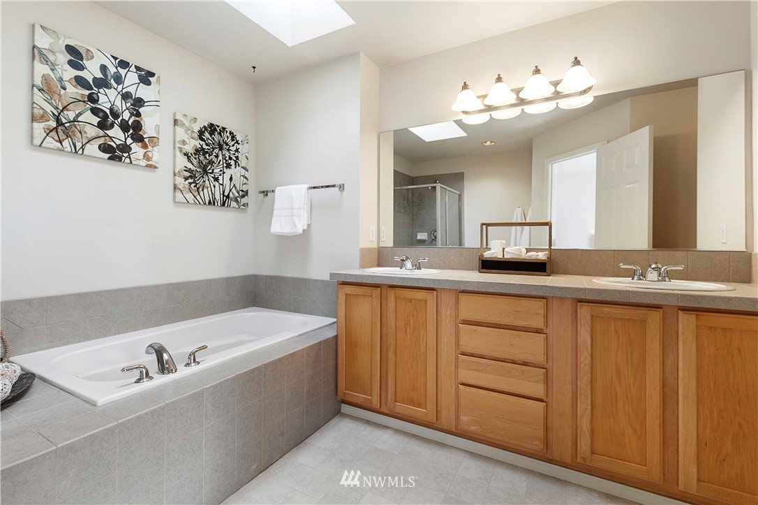 20117 Bartlett Road Bothell, WA 98012 - Photo 23 of 32 a bathroom with a tub a double vanity sink and a mirror