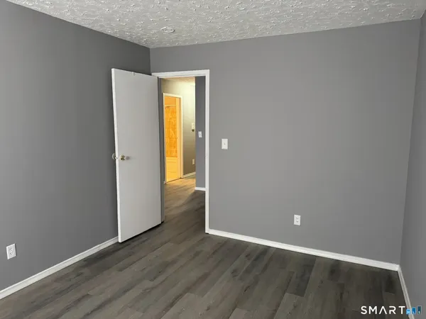 a view of an empty room with wooden floor and closet