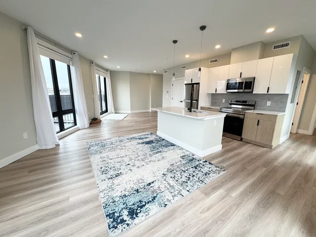 a large kitchen with kitchen island a sink a stove a wooden floor a dining table and chairs