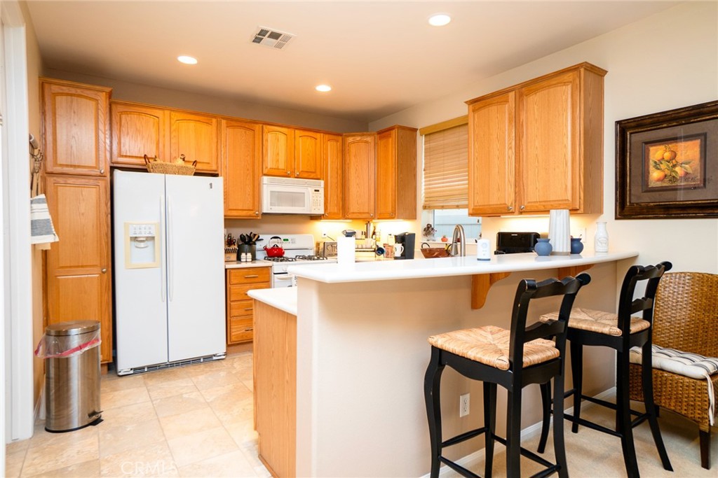 1165 Wisteria Way Beaumont, CA 92223 - Photo 18 of 49 a kitchen with stainless steel appliances a refrigerator a sink a stove a dining table and chairs