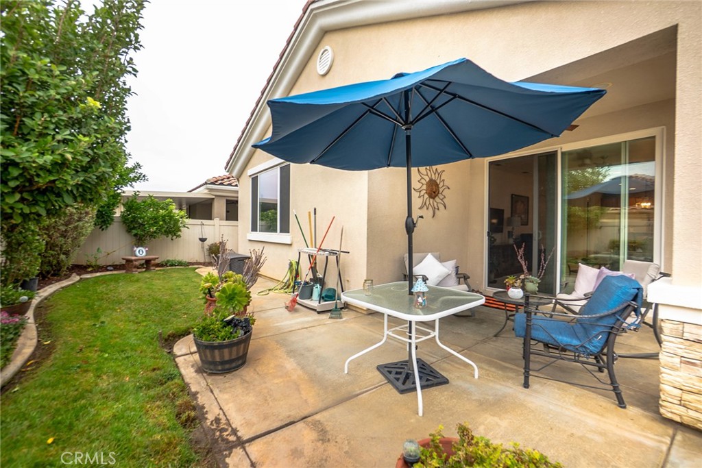 1165 Wisteria Way Beaumont, CA 92223 - Photo 35 of 49 a patio with a table and chairs under an umbrella