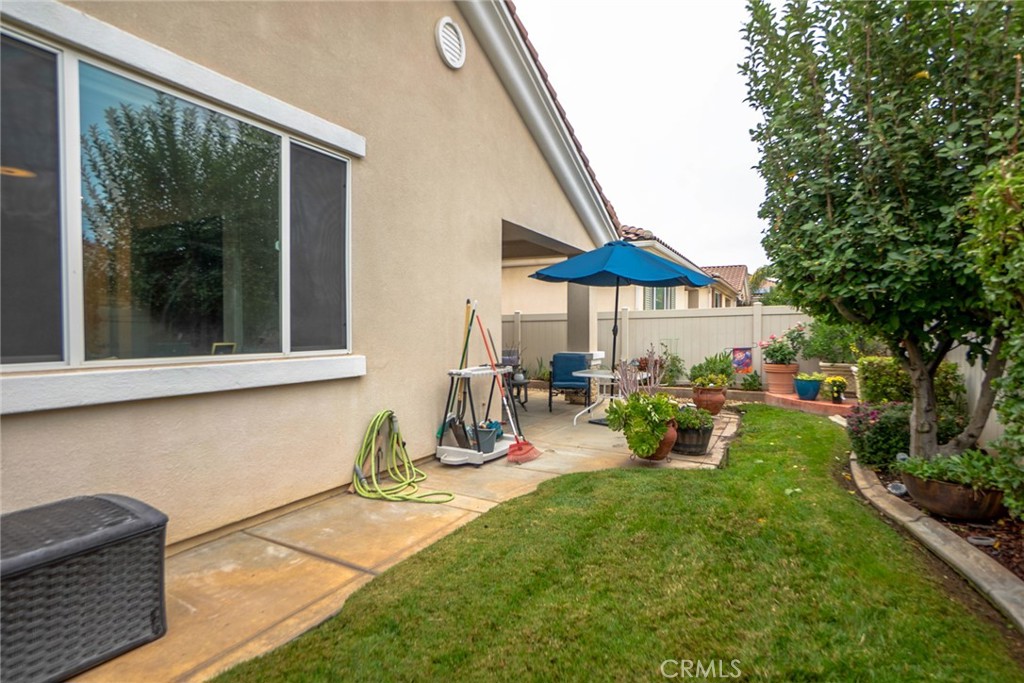 1165 Wisteria Way Beaumont, CA 92223 - Photo 38 of 49 a view of a backyard with table and chairs under an umbrella with a barbeque grill and plants