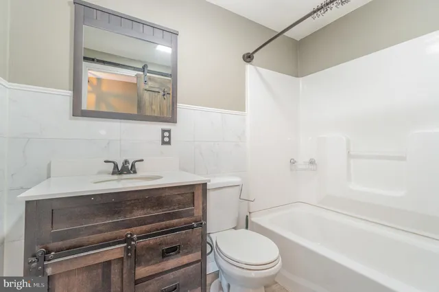 a bathroom with a granite countertop bathtub shower and toilet