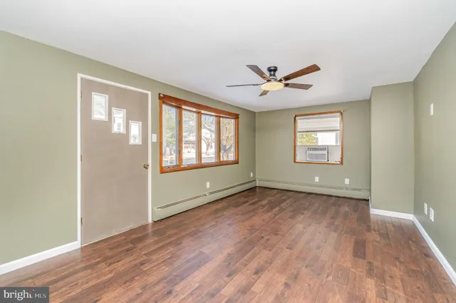 a view of an empty room with a window and wooden floor