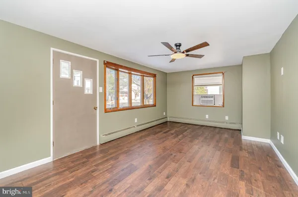 a view of an empty room with a window and wooden floor