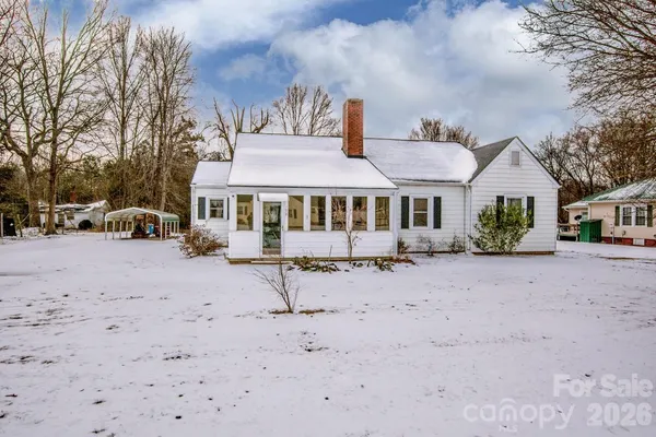 a view of a white house with a yard covered in snow