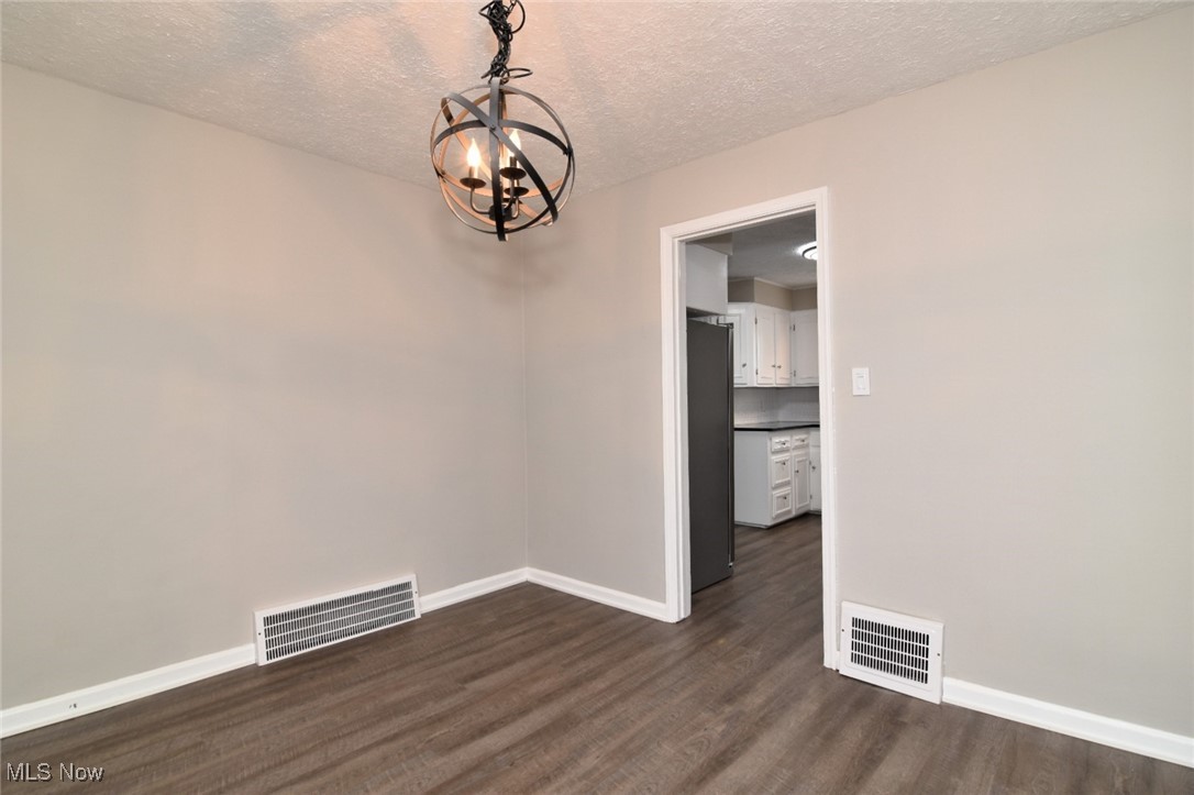 1443 Churchill Road Lyndhurst, OH 44124 - Photo 10 of 39 Spare room with a textured ceiling, dark wood-style flooring, and a chandelier