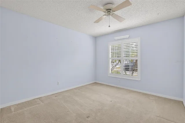 an empty room with a window and a fan