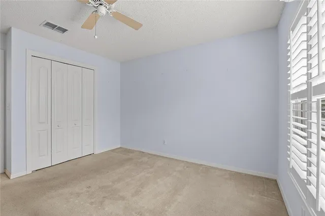 an empty room with windows and fan