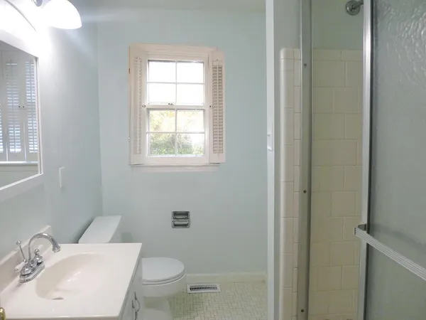 a bathroom with a toilet a sink a mirror and a window