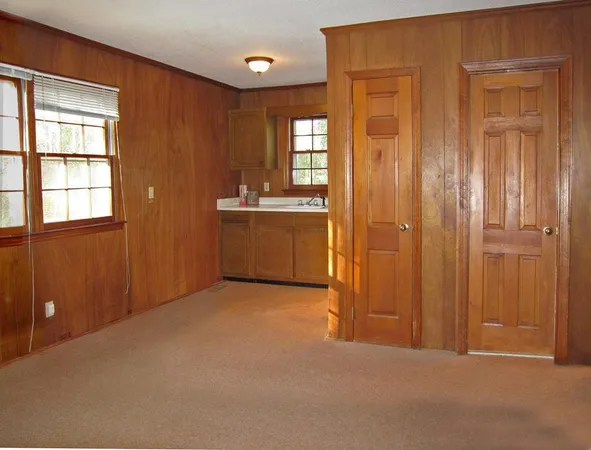 an empty room with windows cabinet and bathroom