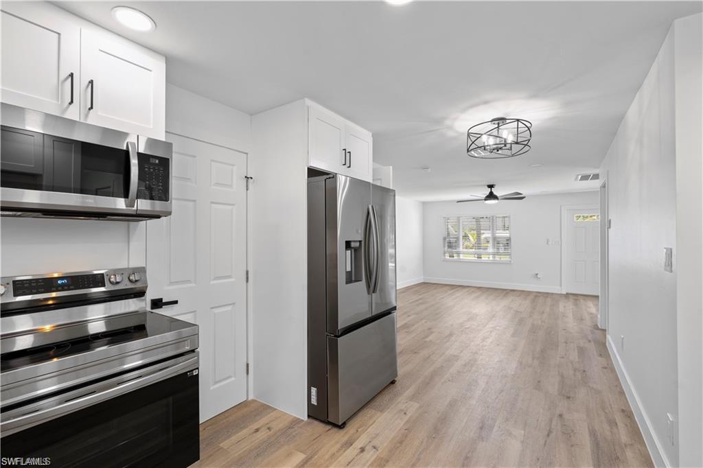 1855 Danford Street, Unit A Naples, FL 34112 - Photo 22 of 22 Kitchen with appliances with stainless steel finishes, white cabinets, light wood-type flooring, open floor plan, and a ceiling fan