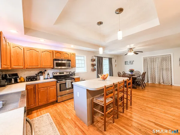 a kitchen with stainless steel appliances kitchen island granite countertop a table chairs and a refrigerator