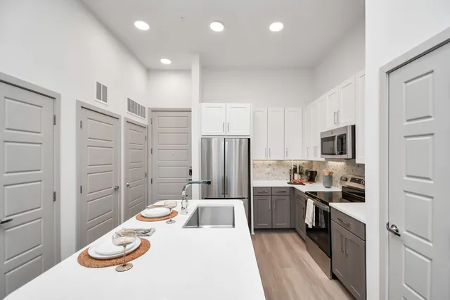 a kitchen with stainless steel appliances kitchen island granite countertop a sink and refrigerator