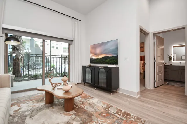 a living room with furniture a floor to ceiling window and a flat screen tv
