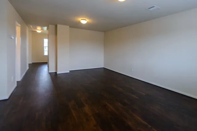 a view of an empty room with wooden floor and a sink