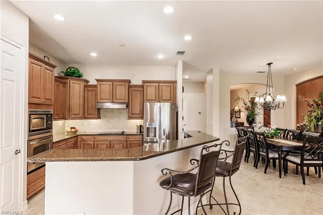 a kitchen with kitchen island granite countertop wooden cabinets and stainless steel appliances