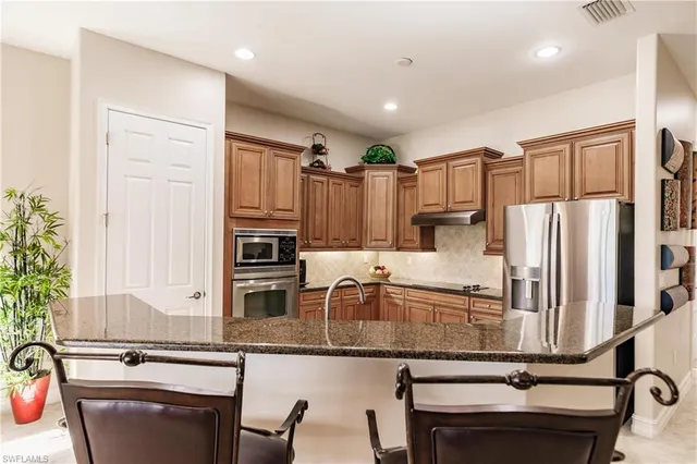 a kitchen with stainless steel appliances granite countertop a refrigerator and a stove top oven
