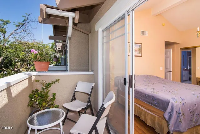 a balcony with table and chairs potted plants