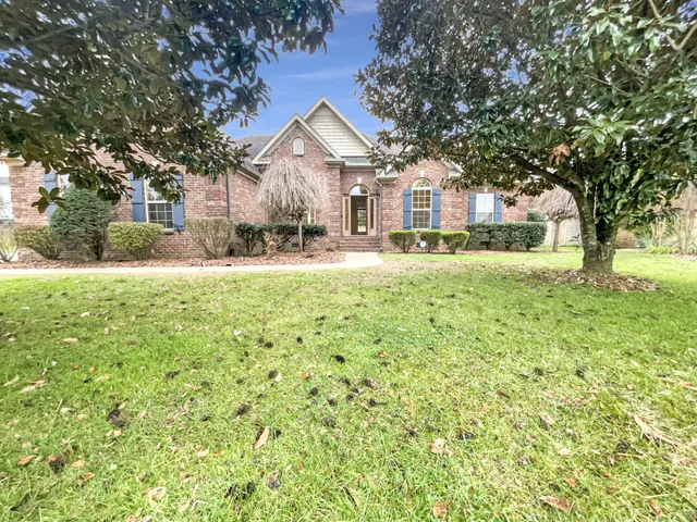 a view of a house with a yard and large tree