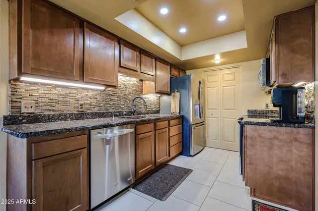a kitchen with stainless steel appliances granite countertop a sink stove and refrigerator