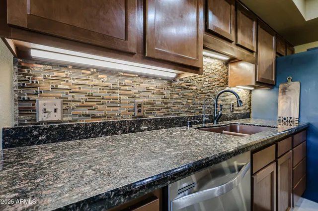 a kitchen with a granite countertop sink and cabinets