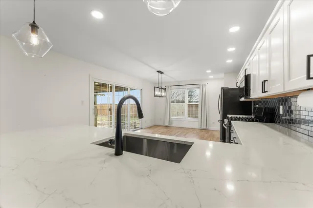 a large kitchen with stainless steel appliances granite countertop a sink a stove and a refrigerator