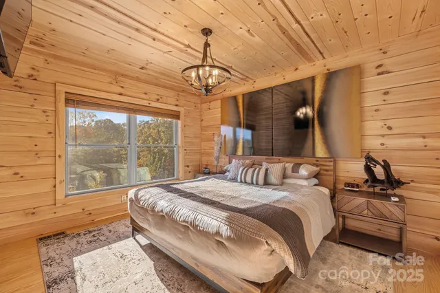 a bedroom with a bed a large window and painting on the wall