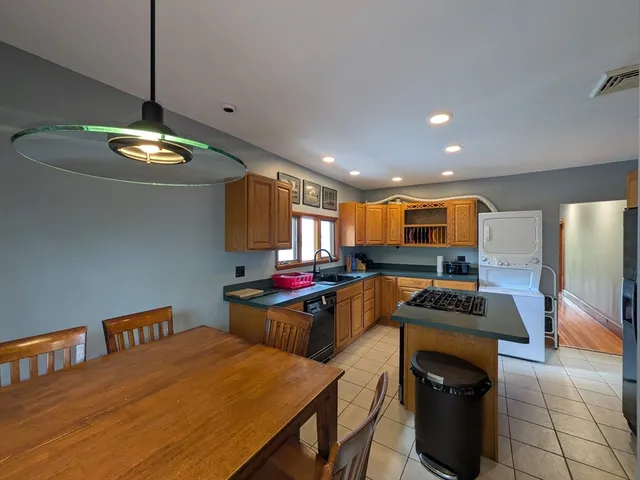 a kitchen with stainless steel appliances a stove a refrigerator white cabinets and a dining table