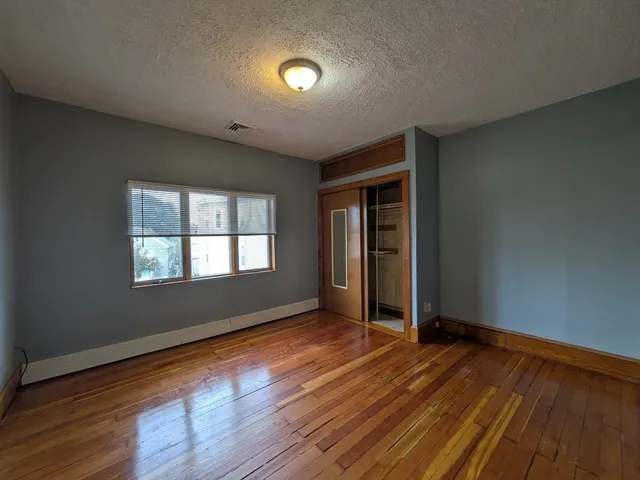 a view of an empty room with glass door and wooden floor