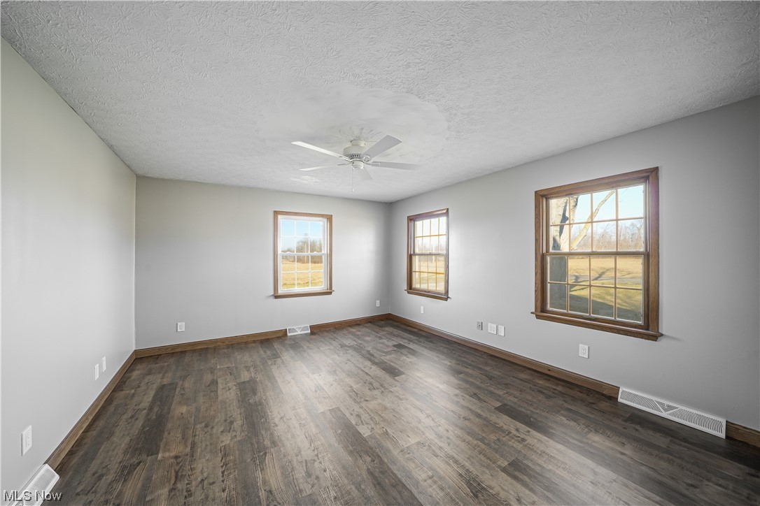 10258 Gilbert Road Newton Falls, OH 44444 - Photo 16 of 37 Empty room with ceiling fan, a textured ceiling, and dark wood-type flooring