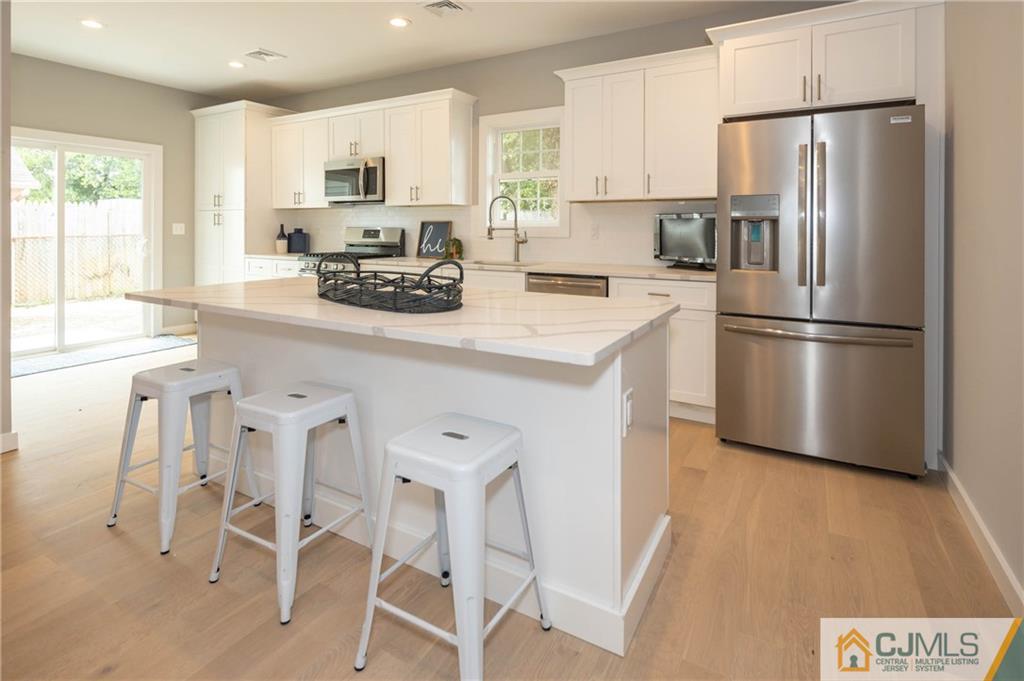 37 Markham Road Edison, NJ 08817 - Photo 3 of 30 a kitchen with a refrigerator a stove a sink and white cabinets with wooden floor