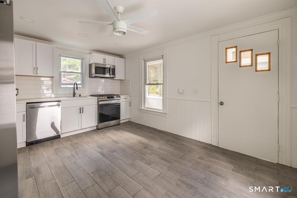 106 Wooster Street Shelton, CT 06484 - Photo 3 of 9 a kitchen with stainless steel appliances granite countertop a stove top oven a sink dishwasher and a refrigerator with wooden floor