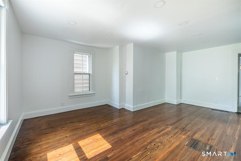 106 Wooster Street Shelton, CT 06484 - Photo 4 of 9 an empty room with wooden floor and windows