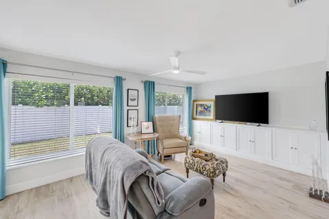 a living room with furniture a flat screen tv and a large window